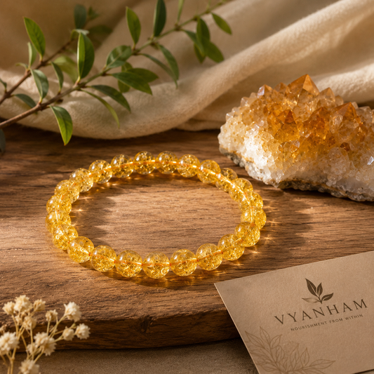 Citrine bracelet resting on a stone coaster beside a raw citrine crystal on linen and wood