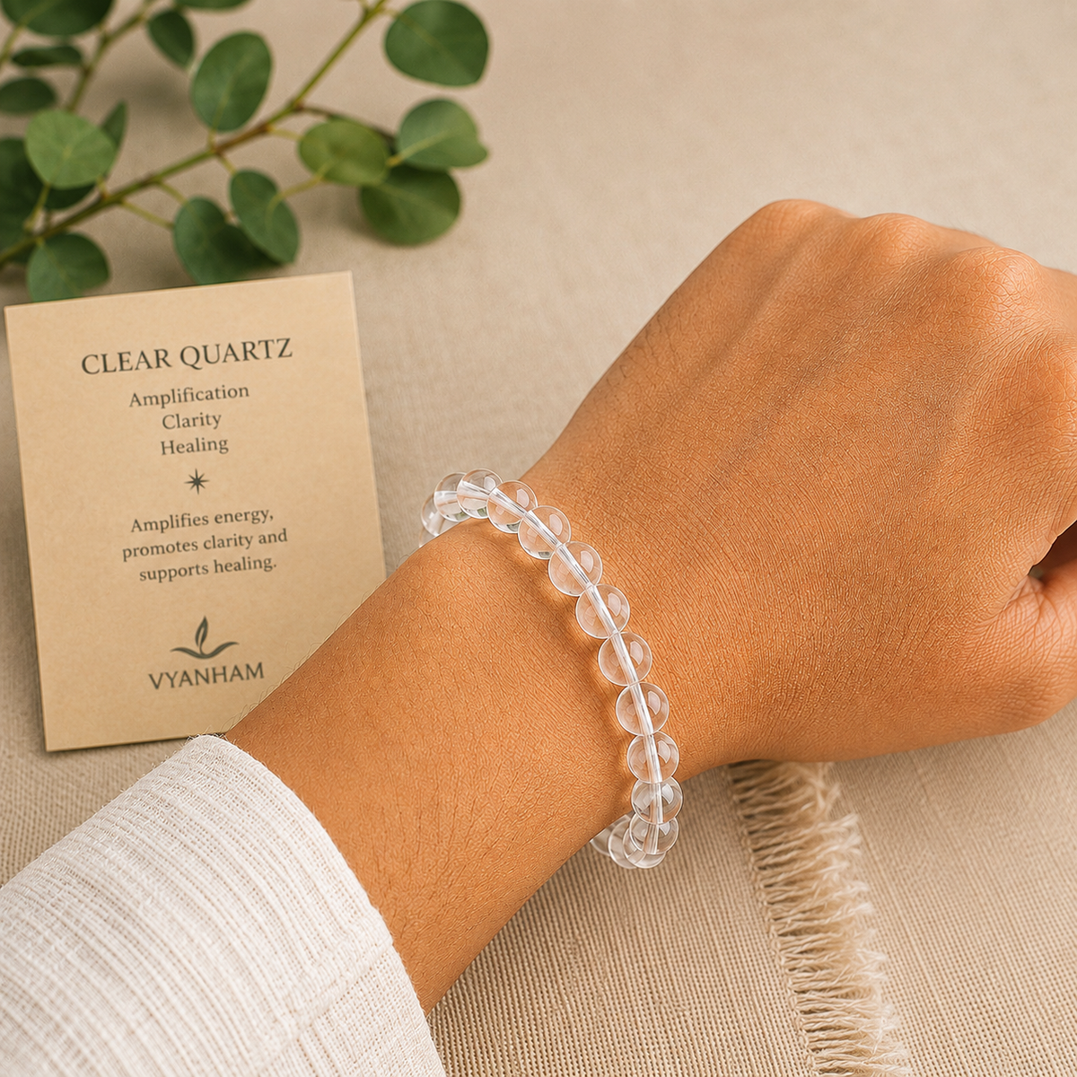 Clear quartz bracelet worn on a wrist beside the Vyanham intention card