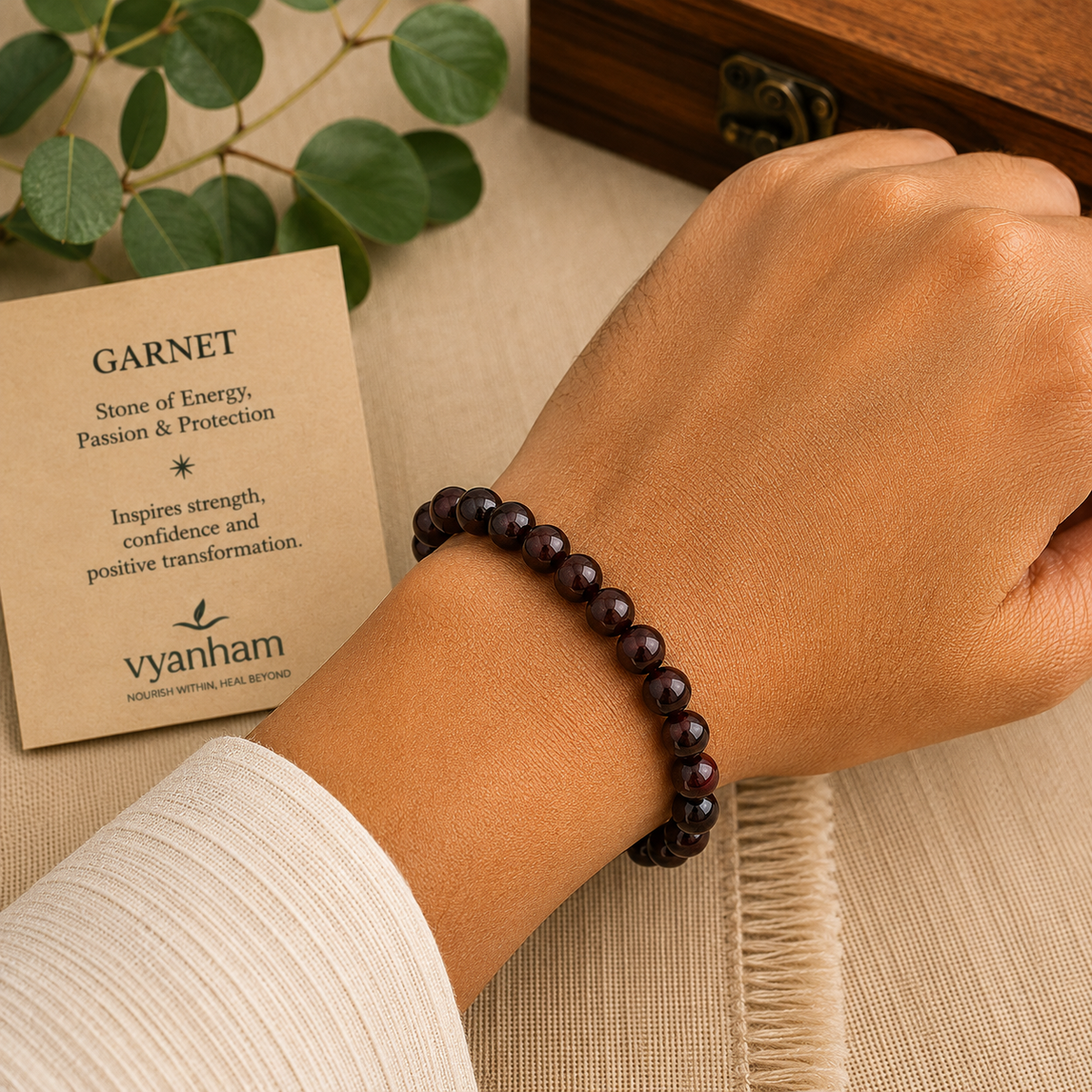Garnet bracelet worn on a wrist beside the Vyanham intention card