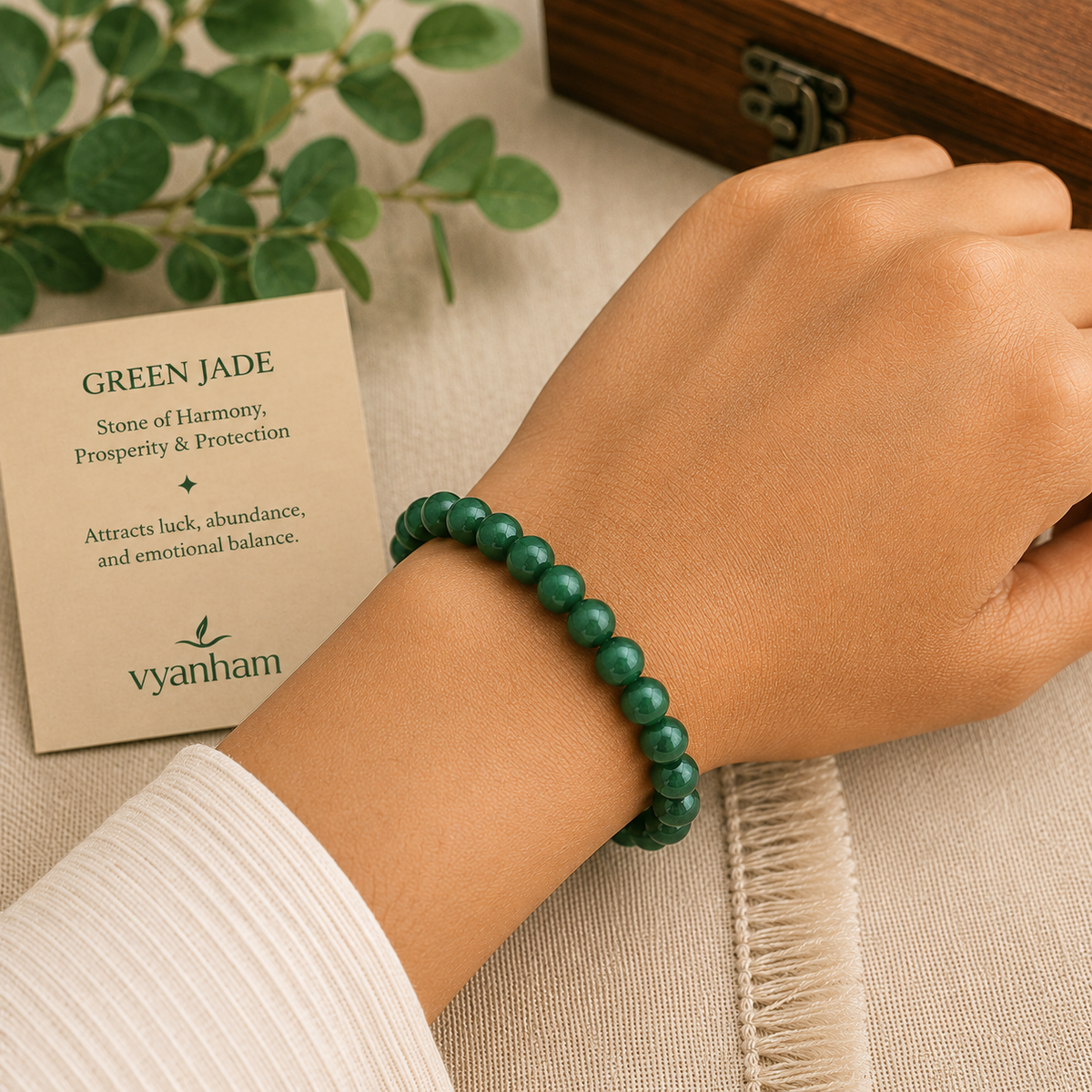 Green jade bracelet worn on a wrist beside the Vyanham intention card