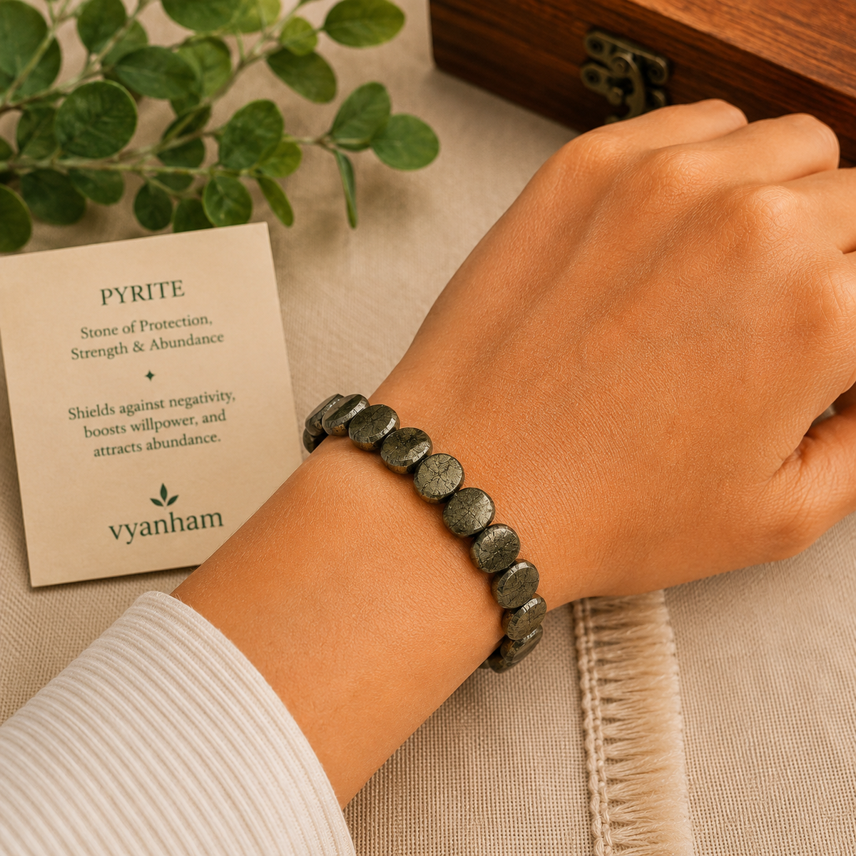 Pyrite oval-cut bracelet worn on a wrist beside the Vyanham intention card