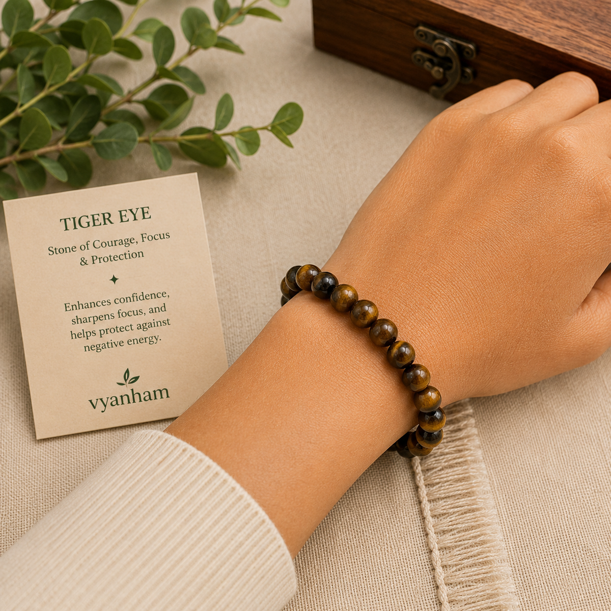 Tiger eye bracelet worn on a wrist beside the Vyanham intention card